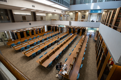 Students studying at the long tables inside the Law Library. 